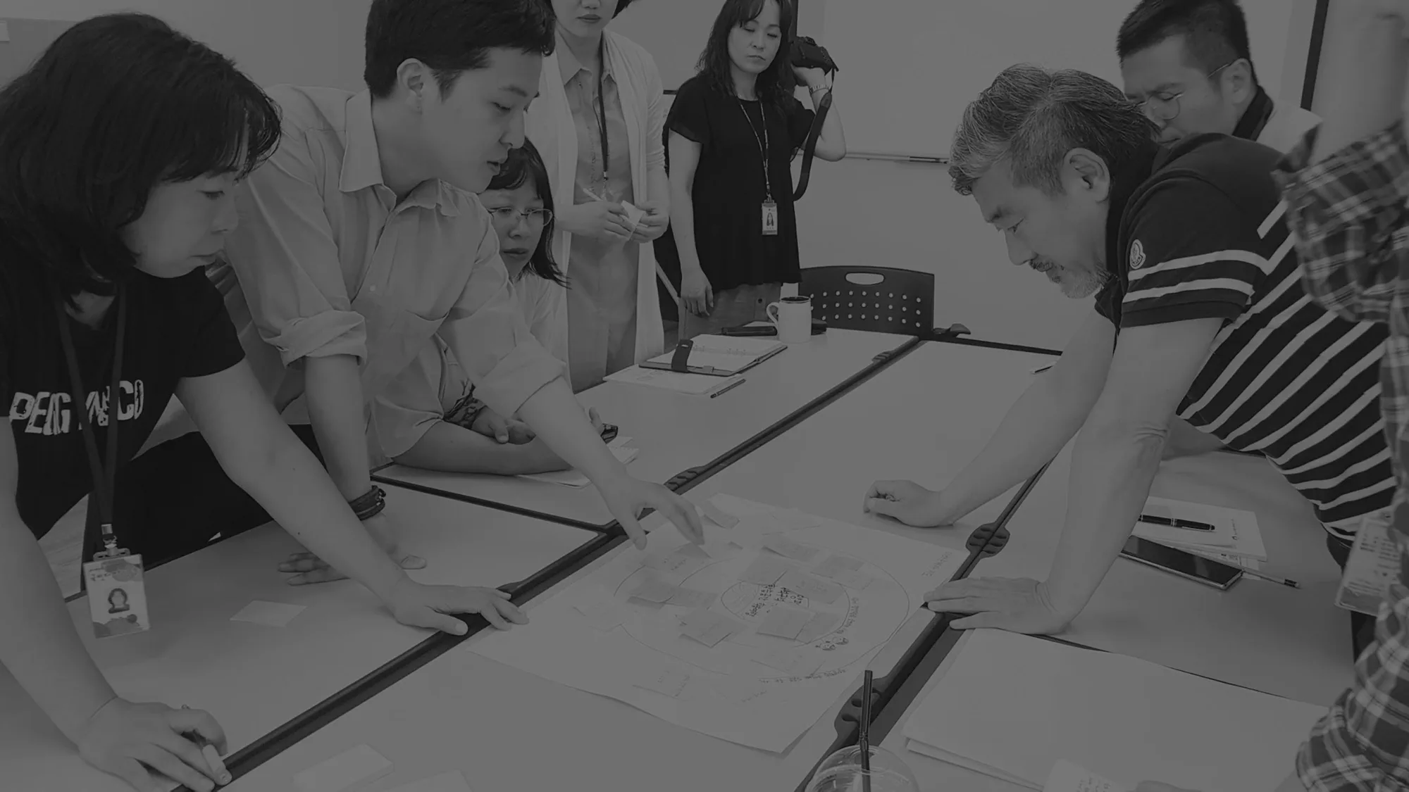 비저블엑스 워크숍에서 참여자들이 테이블에 모여 자료를 보며 이야기하는 모습